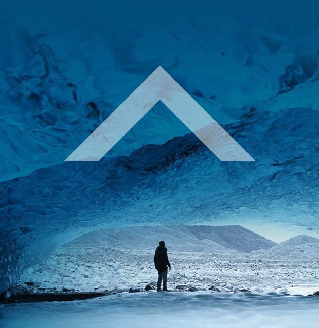 A person steps out of a cave under a glacier. Text: News at U of T for alumni and friends, the Defy Gravity caret symbol 