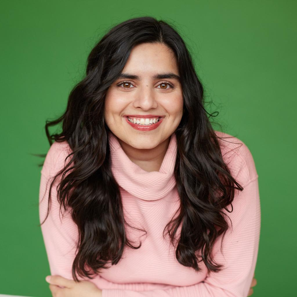 Haleema Khan leans forward, smiling with arms folded 