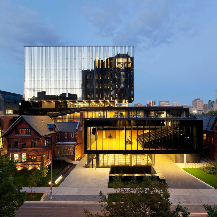 The Rotman School of Management buildings are pictured lit up at night-time 