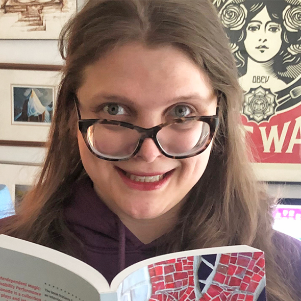 Jessica Watkin looking at camera holding a book  