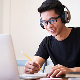 student with headphones on at a notebook computer