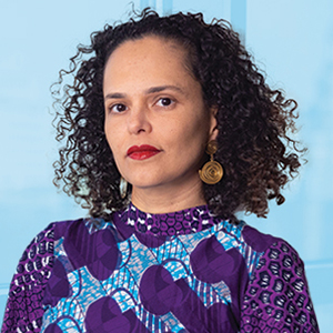 A woman wearing a sparkly purple top looks at the camera.