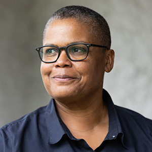 A woman with short hair and glasses looks off to the left