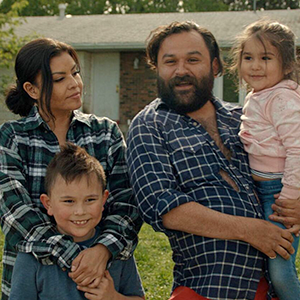 A family of four, including two young children, look at the camera.